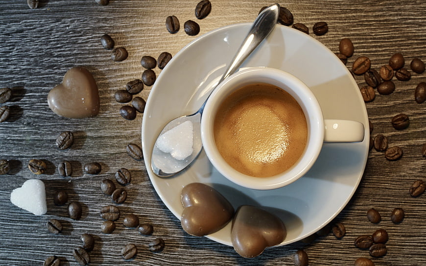 Top view of espresso with heart chocolates and sugar on wood