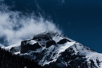 Snowy Mountain Peak with Clouds and Forest
