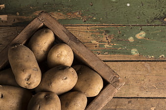 Fresh raw potatoes in rustic wooden crate on vintage table