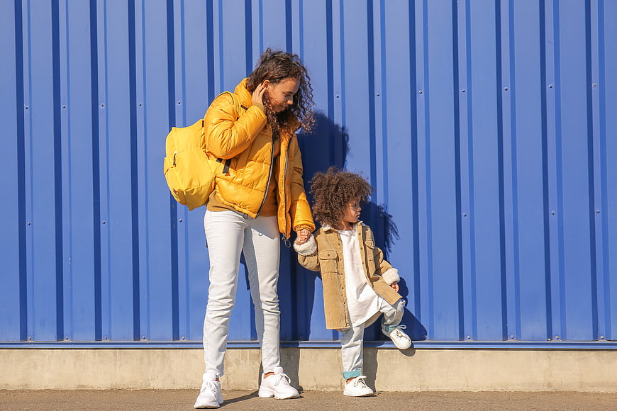 Mother and daughter holding hands against blue wall