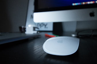 Close-up of white Apple Magic Mouse on dark desk