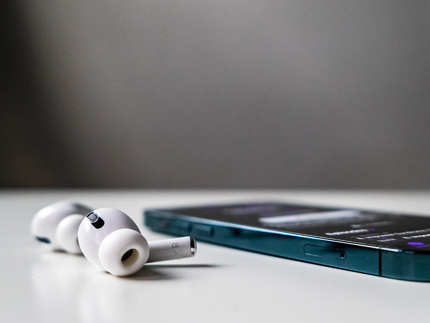 White Wireless Earbuds and Smartphone on White Desk