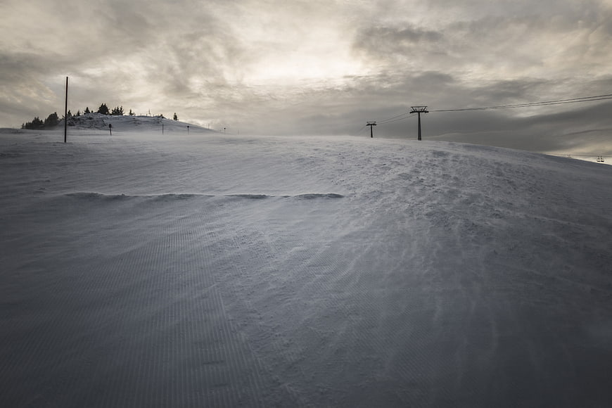 Snowy ski slope with chairlift and cloudy winter sky
