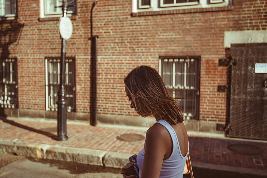 Woman walking on urban brick street in white tank top