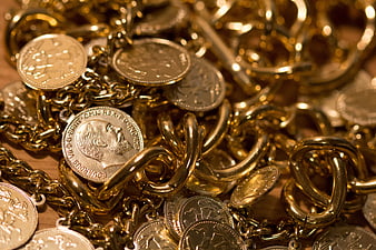Close-up of gold chains and coins on wooden surface