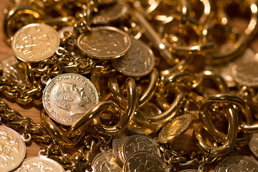 Close-up of gold chains and coins on wooden surface