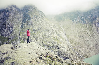 Hiker in Red Jacket Standing on Mountain Peak Overlooking Valley