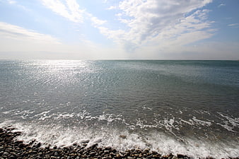 Sunlit Ocean Waves on Rocky Pebble Beach