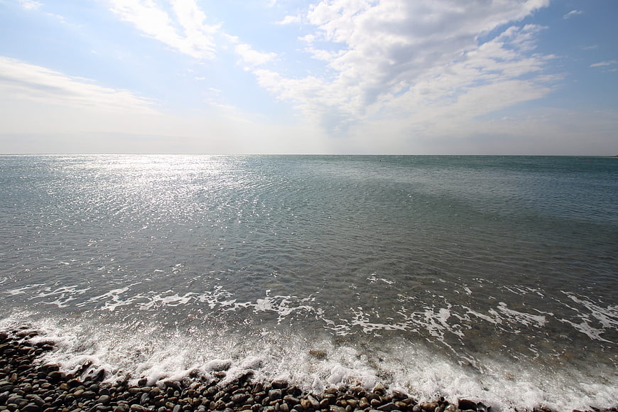 Sunlit Ocean Waves on Rocky Pebble Beach