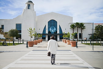 Woman Walking Towards White Spanish Colonial Building