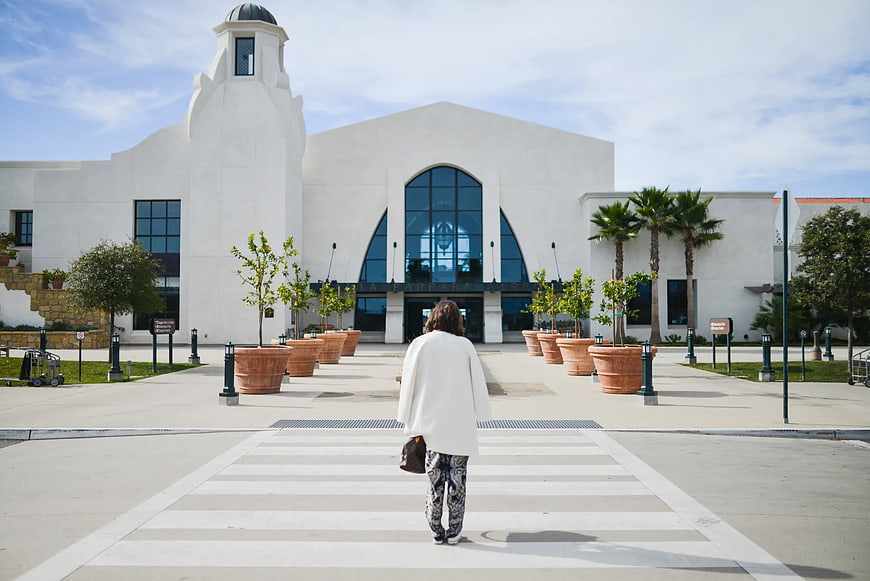 Woman Walking Towards White Spanish Colonial Building