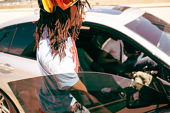 Man with dreadlocks and sunglasses getting into a white car