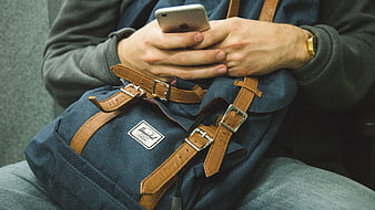 Man using smartphone with blue backpack on lap