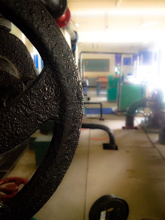 Close-up of textured black industrial valve wheel in workshop