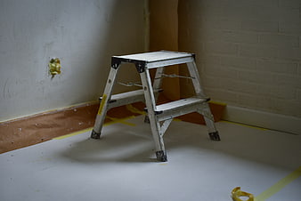 Metal step ladder in room under renovation with taped floor