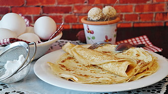 Homemade crepes with eggs and sugar on rustic table