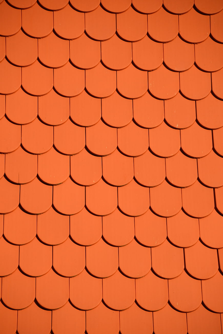 Close-up of orange roof tiles in a repeating fish-scale pattern