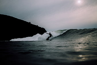 Silhouette of Surfer Riding Wave at Dusk