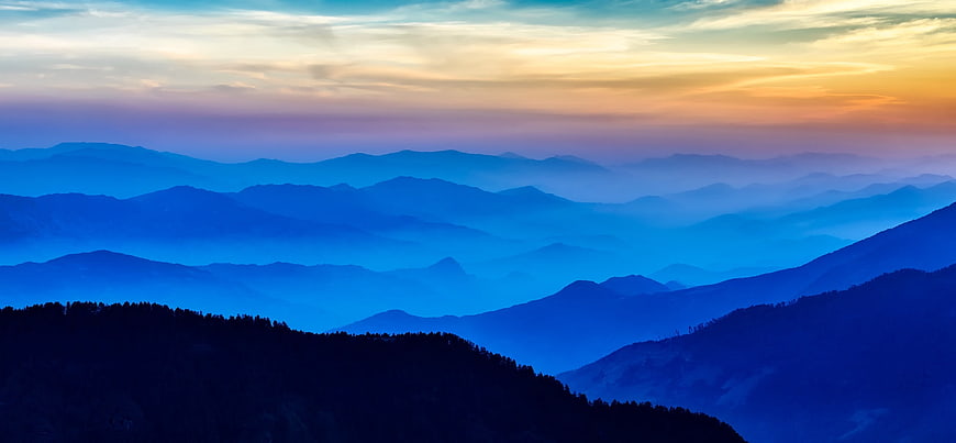 Panoramic Blue Mountain Ranges at Sunrise with Misty Layers
