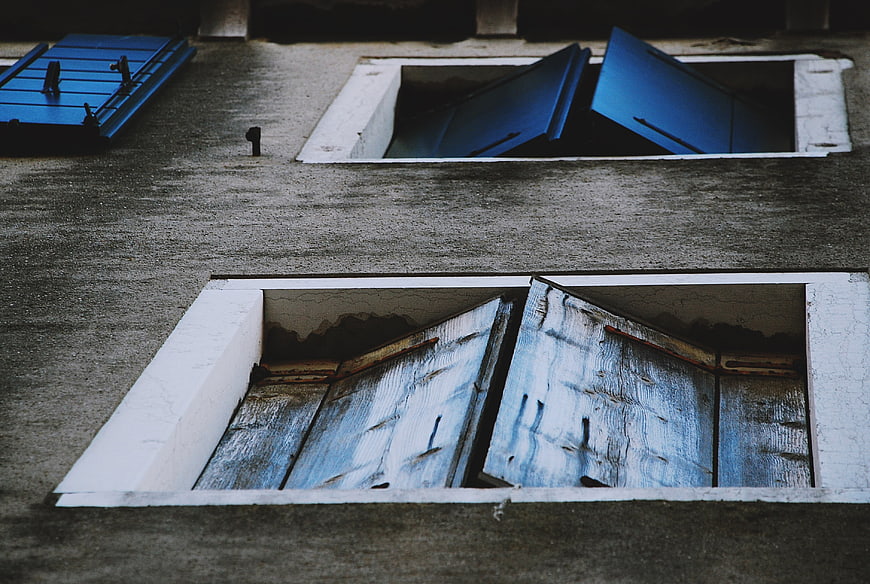 Weathered blue wooden shutters on a textured concrete wall