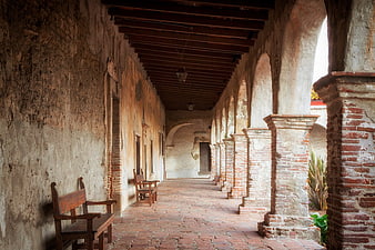Historic Mission Corridor With Arched Columns And Wooden Benches