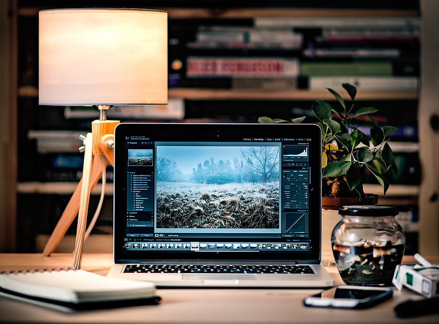 Laptop displaying photo editing software on a creative workspace desk