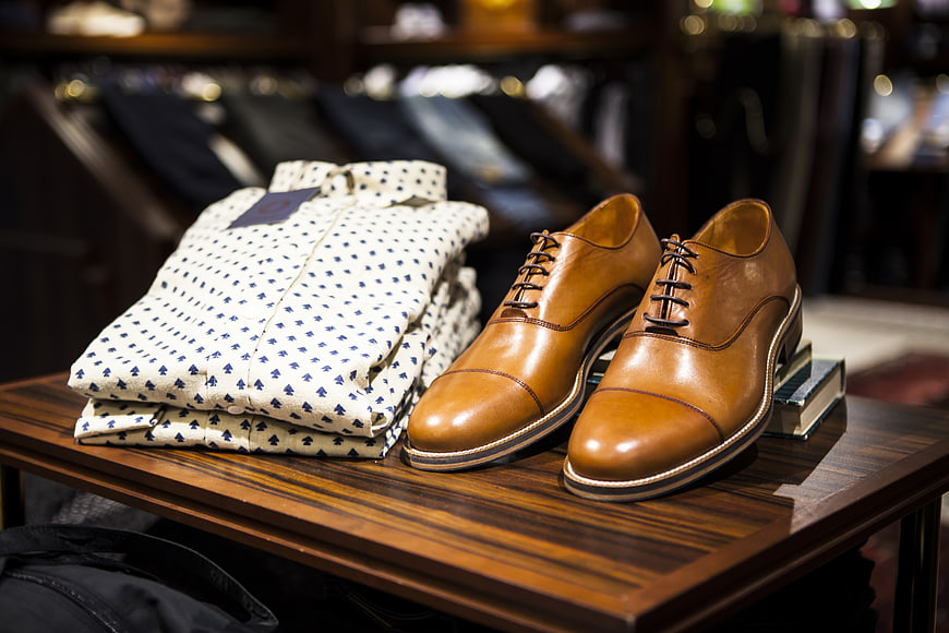Brown leather shoes and patterned shirt on wooden table