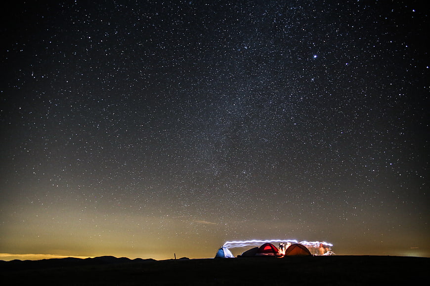 Camping Tents Under Starry Night Sky with Light Trails