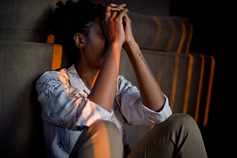 Woman Sitting on Couch with Hands on Head in Dramatic Light