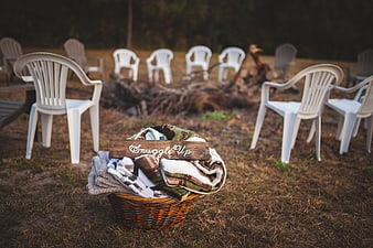 Basket of blankets with 'Snuggle Up' sign near outdoor fire pit