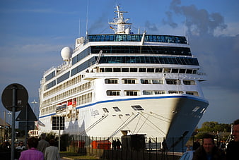Large white cruise ship docked at port with people