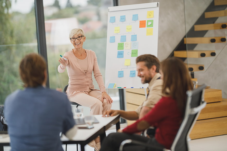 Senior female business leader leading a team meeting with sticky notes