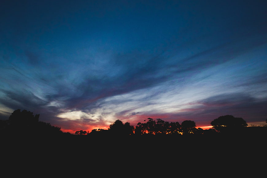 Dramatic Sunset Sky with Silhouetted Trees and Clouds