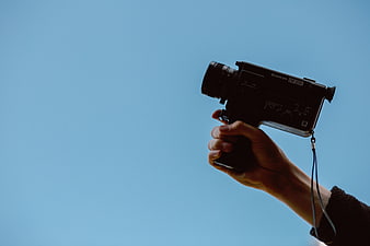 Hand holding vintage Sankyo Super 8 camera against blue sky