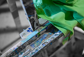 Close-up of wooden easel with green cloth and paint splatters