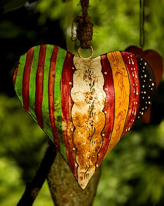 Hand-painted rustic heart ornament hanging in a garden