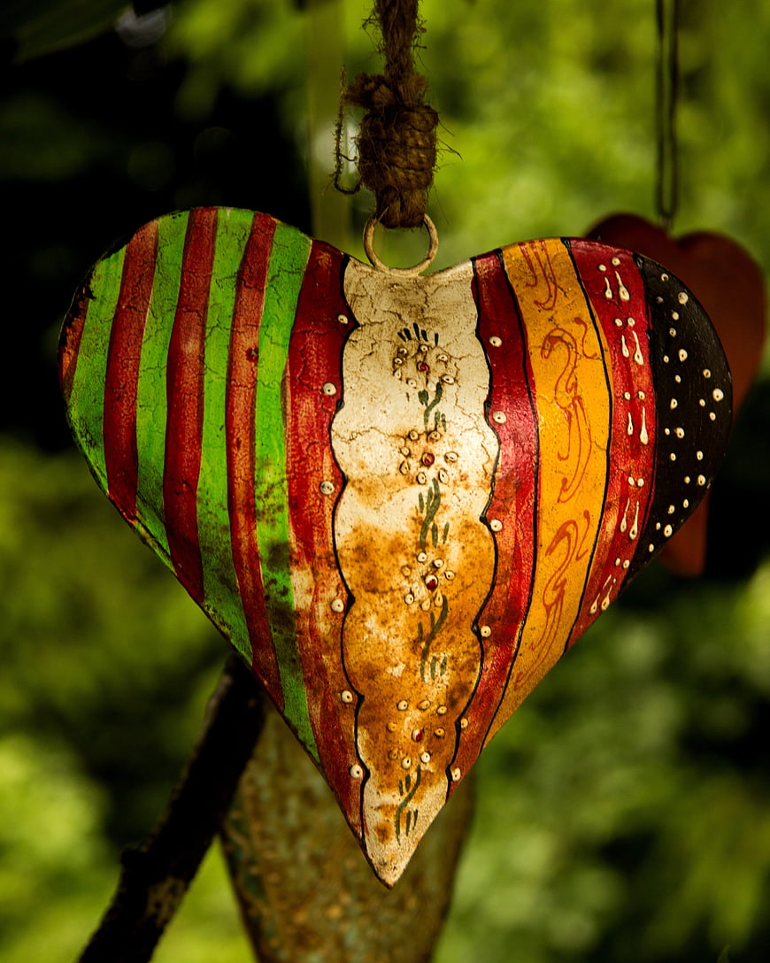 Hand-painted rustic heart ornament hanging in a garden