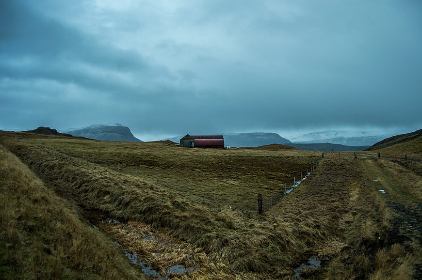 Lone red barn in Icelandic landscape with mountains