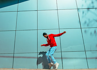 Man in Red Hoodie Dancing Against Blue Wall