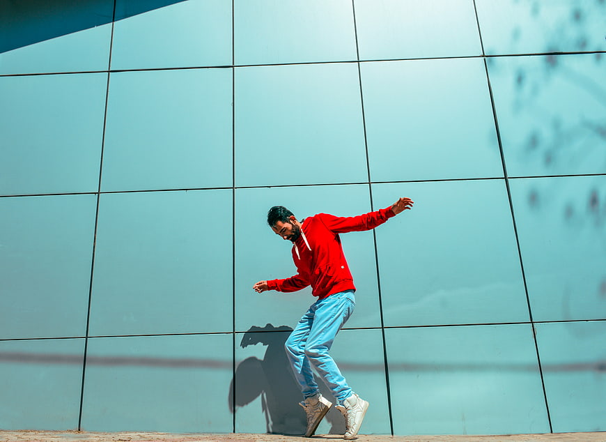 Man in Red Hoodie Dancing Against Blue Wall