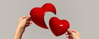 Hands holding two halves of a red heart puzzle