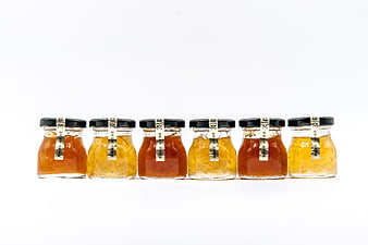 Six glass jars of bird's nest soup with black lids on white background