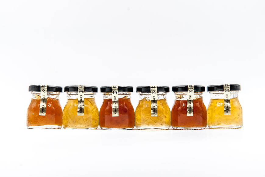 Six glass jars of bird's nest soup with black lids on white background