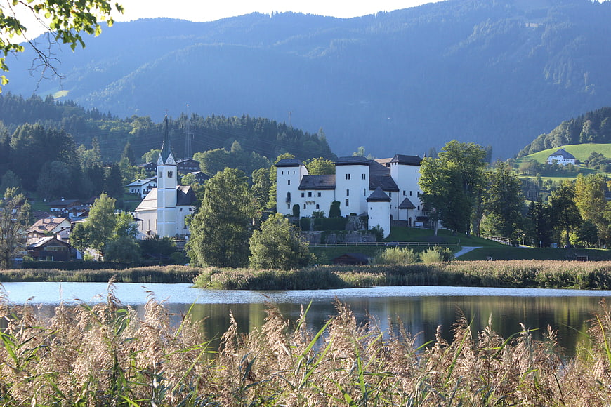White castle and church on lake shore with mountains