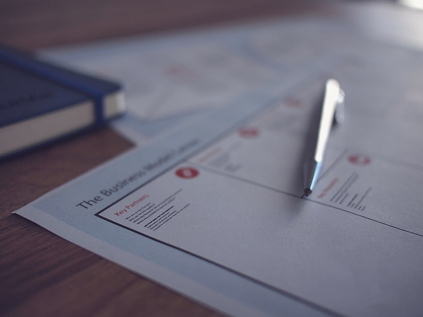 Business Model Canvas Document with Pen on Desk