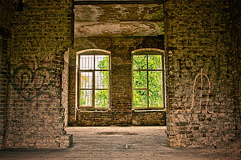 Interior of Abandoned Brick Building with Arched Windows and Overgrown Greenery
