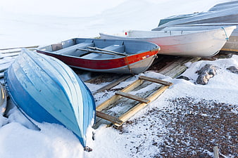 Colorful wooden boats resting on snow in winter