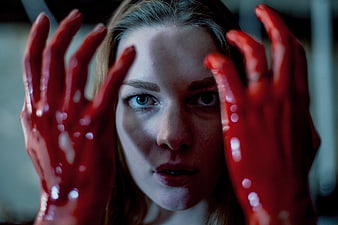 Woman with blood-covered hands looking at camera