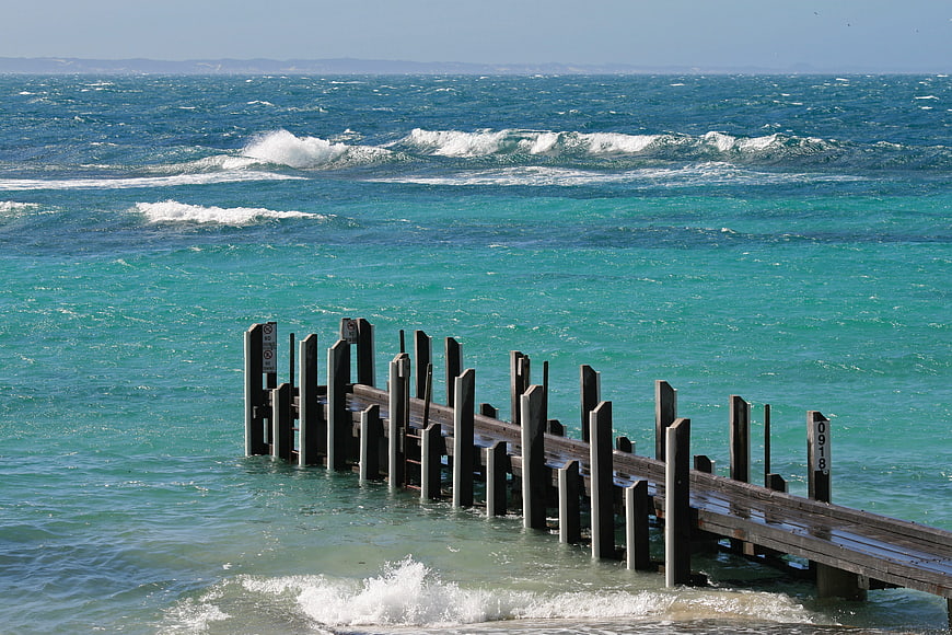 Weathered wooden jetty extending into turquoise ocean waves