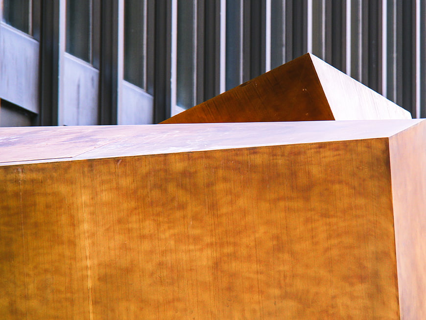 Abstract geometric copper sculpture against modern industrial architecture